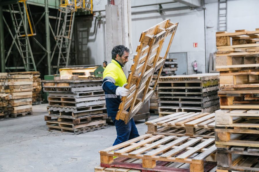 Warehouse worker handling wooden pallets